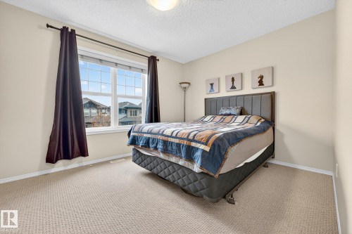 The room features a large window with white framing, providing natural light, and is complemented by light-colored walls and carpeting - 219 60 Street, Edmonton, AB - Indoor Photo Showing Bedroom