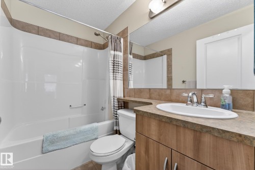 Bathroom featuring a shower and bathtub combination with tiled surround, a vanity with a countertop, an undermount sink, and a mirror - 219 60 Street, Edmonton, AB - Indoor Photo Showing Bathroom