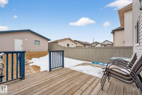 This property features a wooden deck with blue railings, a fenced yard, and a detached building with beige siding and a blue roof trim - 219 60 Street, Edmonton, AB - Outdoor With Deck Patio Veranda With Exterior