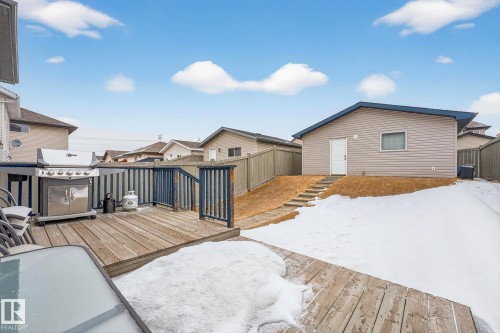 The property features a wooden deck with a railing, a detached building with siding, and a sloped yard - 219 60 Street, Edmonton, AB - Outdoor With Exterior