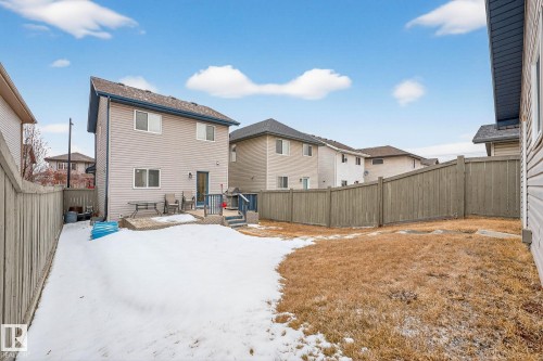 The property features a fenced yard with a partially snow-covered lawn and a patio area accessible from the building - 219 60 Street, Edmonton, AB - Outdoor With Exterior