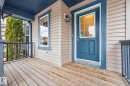 The property features an inviting front porch with wood decking, a blue paneled entry door with a window, and complementing blue trim around the windows and porch railings - 219 60 Street, Edmonton, AB  - Outdoor With Deck Patio Veranda With Exterior 