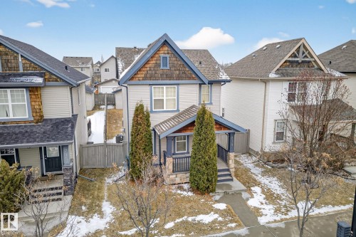 The property features a charming exterior with light-colored siding, a dark roof, and decorative wooden shingles on the gables and porch canopy - 219 60 Street, Edmonton, AB - Outdoor With Facade
