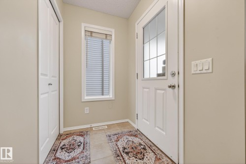 The entryway features a white front door with an upper glass pane, a window with blinds, and light neutral-toned walls - 219 60 Street, Edmonton, AB - Indoor Photo Showing Other Room