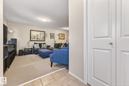 The living area features carpeted flooring and recessed lighting, with a wall-mounted piece of art - 219 60 Street, Edmonton, AB - Indoor Photo Showing Other Room