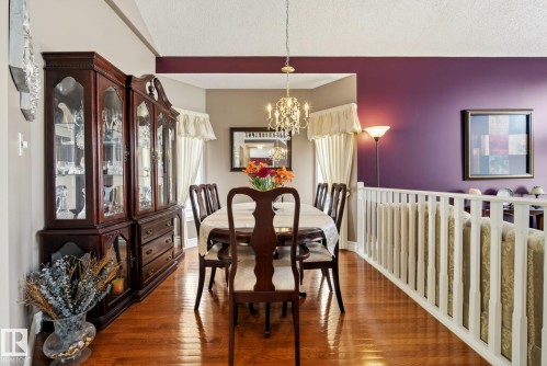 The dining area features gleaming hardwood floors, a decorative chandelier, and a purple accent wall - 12815 156 Avenue, Edmonton, AB - Indoor Photo Showing Dining Room
