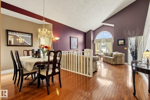 The interior features rich hardwood flooring, a vaulted ceiling, and an arched window - 12815 156 Avenue, Edmonton, AB - Indoor Photo Showing Dining Room