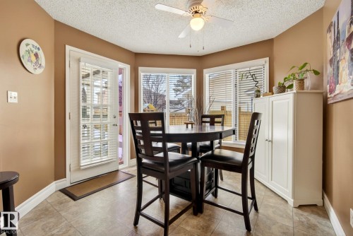 This dining area features neutral-toned walls, tile flooring, and a ceiling fan with integrated lighting - 12815 156 Avenue, Edmonton, AB - Indoor Photo Showing Dining Room