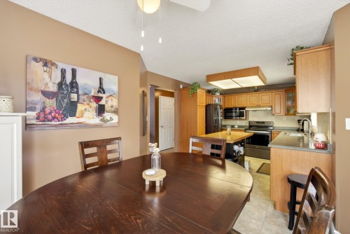 The dining area features a dark wood table and chairs, with a view of the kitchen - 12815 156 Avenue, Edmonton, AB - Indoor