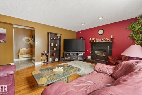Living area featuring hardwood floors, a fireplace with a black tile surround and mantel, and recessed lighting - 12815 156 Avenue, Edmonton, AB - Indoor Photo Showing Living Room With Fireplace