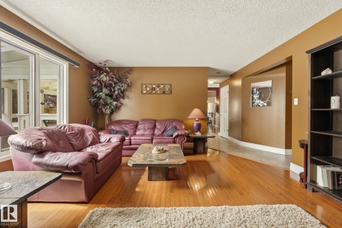 Living room featuring hardwood floors, large windows providing natural light, and a built-in bookshelf - 12815 156 Avenue, Edmonton, AB - Indoor Photo Showing Living Room