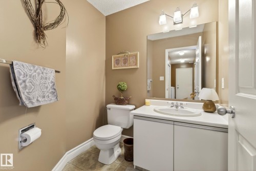 This washroom features a vanity with a white countertop and an integrated sink, a large mirror, and a toilet - 12815 156 Avenue, Edmonton, AB - Indoor Photo Showing Bathroom