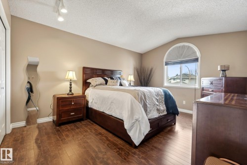 This bedroom features rich wood flooring and a vaulted ceiling with track lighting - 12815 156 Avenue, Edmonton, AB - Indoor Photo Showing Bedroom