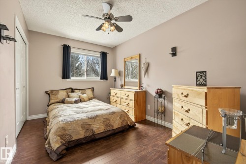 This bedroom features hardwood flooring, a window providing natural light, and a ceiling fan - 12815 156 Avenue, Edmonton, AB - Indoor Photo Showing Bedroom