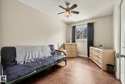 This room features hardwood flooring, a window with dark curtains, and a ceiling fan with integrated lighting - 12815 156 Avenue, Edmonton, AB - Indoor