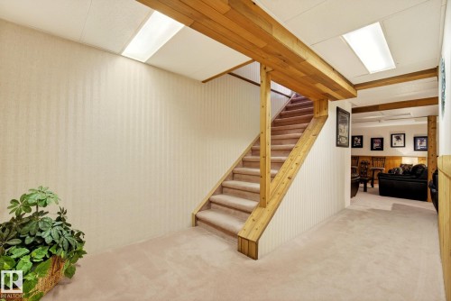 The property features a staircase with carpeted treads and natural wood banisters, complementing the neutral-toned walls - 12815 156 Avenue, Edmonton, AB - Indoor Photo Showing Other Room