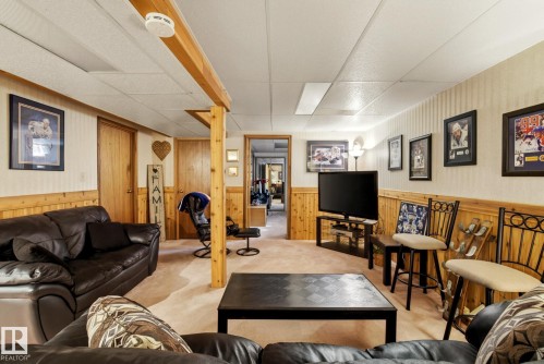 This versatile living space features light-colored carpeting, wood paneling along the lower walls, and a dropped ceiling - 12815 156 Avenue, Edmonton, AB - Indoor