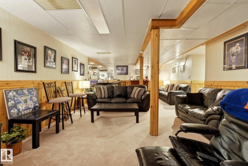 Spacious recreation area featuring a drop ceiling, light-colored carpeting, and wood paneling along the lower walls - 12815 156 Avenue, Edmonton, AB - Indoor