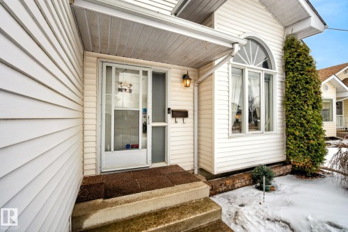 The property features white siding, a front entry with a storm door, and an arched window - 12815 156 Avenue, Edmonton, AB - Outdoor With Exterior