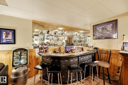 Entertainment area featuring a built-in bar with seating for three, mirrored walls, and wood paneling - 12815 156 Avenue, Edmonton, AB - Indoor Photo Showing Other Room