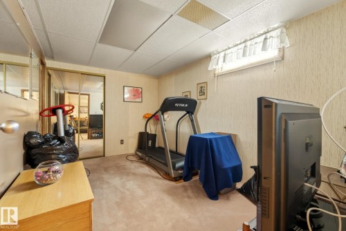 This room features a neutral carpet, textured wallpaper, and a window with blinds - 12815 156 Avenue, Edmonton, AB - Indoor Photo Showing Gym Room