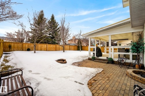 The property features a spacious backyard with a wood fence and mature trees - 12815 156 Avenue, Edmonton, AB - Outdoor