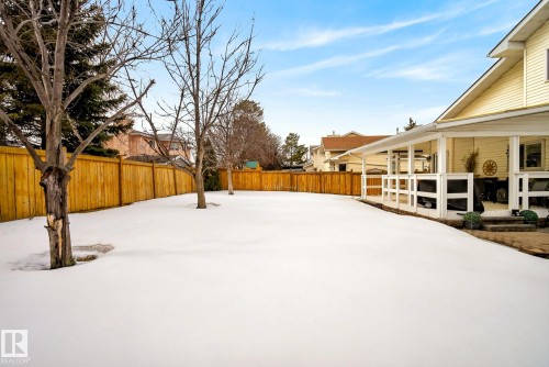 Spacious backyard with a wooden privacy fence, mature trees, and a covered patio area - 12815 156 Avenue, Edmonton, AB - Outdoor