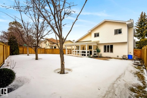 The property features a spacious backyard with a wooden fence and several deciduous trees - 12815 156 Avenue, Edmonton, AB - Outdoor