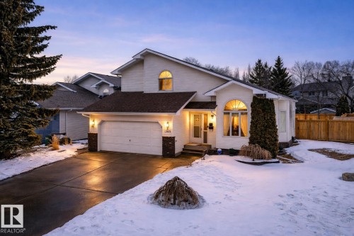 This property features a light-colored exterior, a two-car garage, and an arched window above the front entrance - 12815 156 Avenue, Edmonton, AB - Outdoor