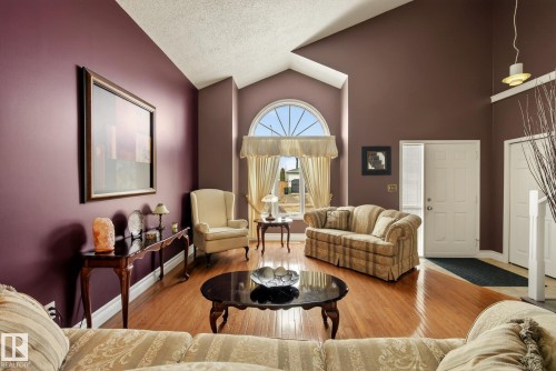The living area features hardwood floors, vaulted ceilings, and a large arched window with a fanlight - 12815 156 Avenue, Edmonton, AB - Indoor Photo Showing Living Room