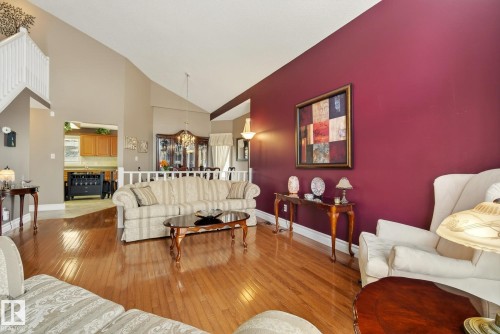 The property features hardwood flooring throughout the main living area, complemented by a striking accent wall - 12815 156 Avenue, Edmonton, AB - Indoor Photo Showing Living Room