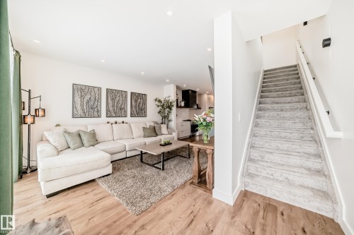 The property features an open-concept living area with light-toned hardwood flooring, a plush area rug, and recessed lighting - 10936 117 Street, Edmonton, AB - Indoor Photo Showing Other Room