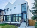 Modern duplex exterior featuring white vertical siding with dark trim accents - 10936 117 Street, Edmonton, AB  - Outdoor 