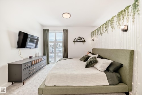 The bedroom features a large window with drapes, providing natural light, and a modern ceiling light fixture - 10936 117 Street, Edmonton, AB - Indoor Photo Showing Bedroom