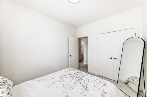 Bedroom featuring white walls, a white ceiling, and white double closet doors with black hardware - 10936 117 Street, Edmonton, AB - Indoor Photo Showing Bedroom