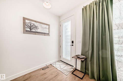 The entry features light-colored walls and wood flooring, complemented by a white door with frosted glass - 10936 117 Street, Edmonton, AB - Indoor Photo Showing Other Room