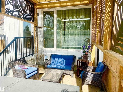 Expansive outdoor deck featuring wood-finish flooring, decorative metal privacy screens with a botanical pattern, and an exterior window - 10936 117 Street, Edmonton, AB - Outdoor With Exterior
