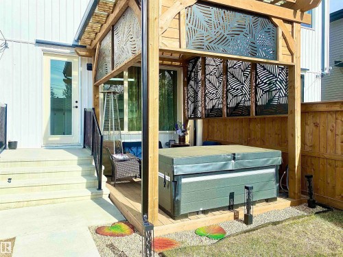Wooden pergola structure featuring decorative privacy screens, a built-in hot tub, and an adjacent deck area - 10936 117 Street, Edmonton, AB - Outdoor With Exterior