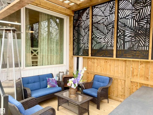 The property features an outdoor patio area with a wooden deck, adorned with decorative screens featuring a leaf motif - 10936 117 Street, Edmonton, AB - Outdoor With Exterior