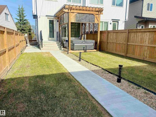 Private backyard featuring a paved walkway, established lawn areas, and a wood privacy fence - 10936 117 Street, Edmonton, AB - Outdoor