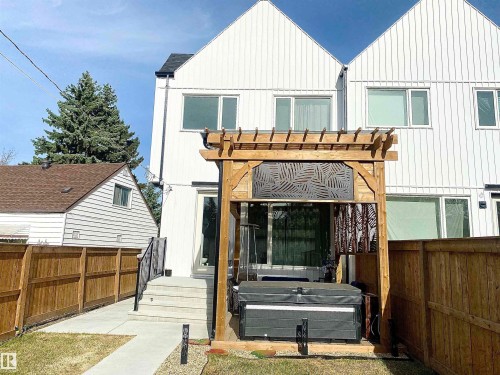 Backyard featuring a wooden pergola with decorative screens, a hot tub, and a concrete patio - 10936 117 Street, Edmonton, AB - Outdoor With Exterior