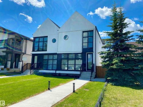 Modern duplex exterior featuring a striking black and white facade, prominent gable roofs, and large grid-pattern windows - 10936 117 Street, Edmonton, AB 