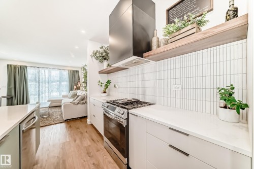 The kitchen features white countertops, a gas range with a black range hood, and a vertical white tile backsplash - 10936 117 Street, Edmonton, AB - Indoor Photo Showing Kitchen With Upgraded Kitchen