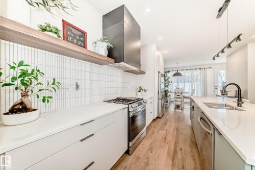 The kitchen features a gas range, stainless steel appliances, a white tile backsplash, and light wood flooring - 10936 117 Street, Edmonton, AB - Indoor Photo Showing Kitchen With Double Sink With Upgraded Kitchen