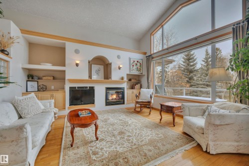 Enjoy the ravine views from the beautifully framed living room. - 615 Twin Brooks Bend, Edmonton, AB - Indoor Photo Showing Living Room With Fireplace