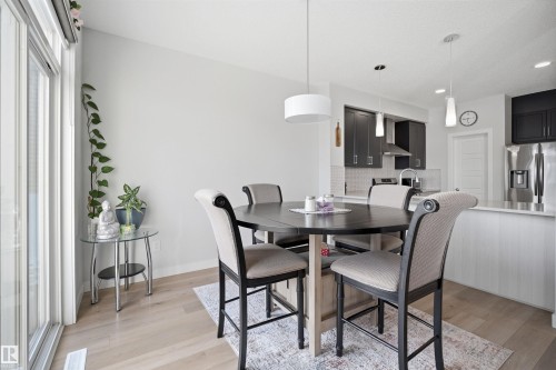 This inviting dining area features light-toned flooring and a drum pendant light fixture - 7017 54 Avenue, Beaumont, AB - Indoor Photo Showing Dining Room