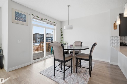 This dining area features light-toned flooring, a round dining table with seating, and a pendant light fixture - 7017 54 Avenue, Beaumont, AB - Indoor Photo Showing Dining Room