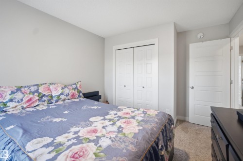 The property features a bedroom with light grey walls, carpeted flooring, and a white closet with bi-fold doors - 7017 54 Avenue, Beaumont, AB - Indoor Photo Showing Bedroom