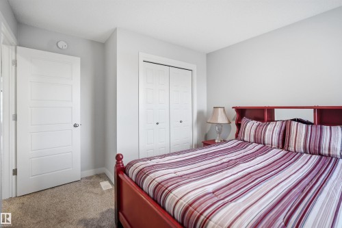 This room features light gray walls, a textured carpeted floor, and a white paneled door - 7017 54 Avenue, Beaumont, AB - Indoor Photo Showing Bedroom