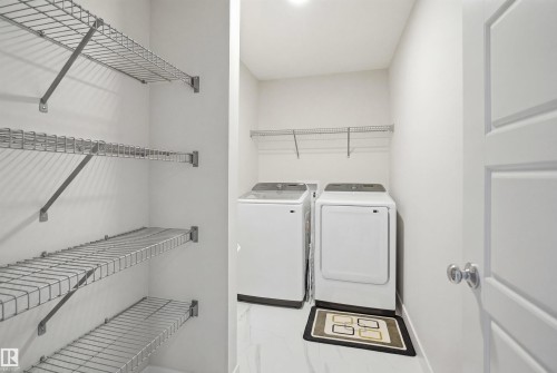 Dedicated laundry area featuring a washer and dryer, white walls, and wire shelving for storage - 7017 54 Avenue, Beaumont, AB - Indoor Photo Showing Laundry Room